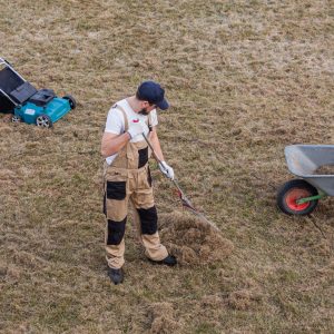 scarifying-lawn-with-rake-scarifier-man-gardener-scarifies-lawn-removal-old-grass-min